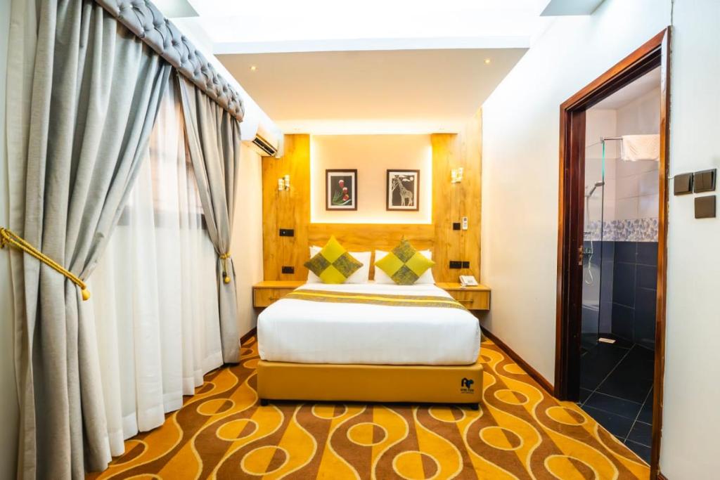 a hotel room with a bed and a window at Afro Park Hotel in Kampala