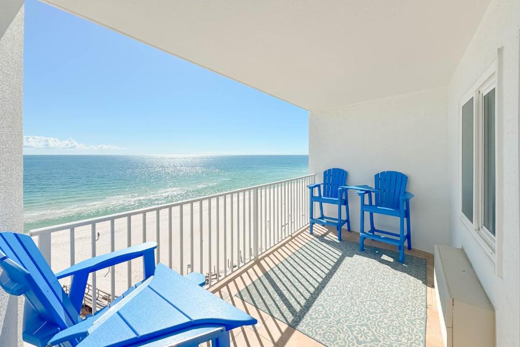 a balcony with two blue chairs and the ocean at Perdido Skye 64 in Pensacola