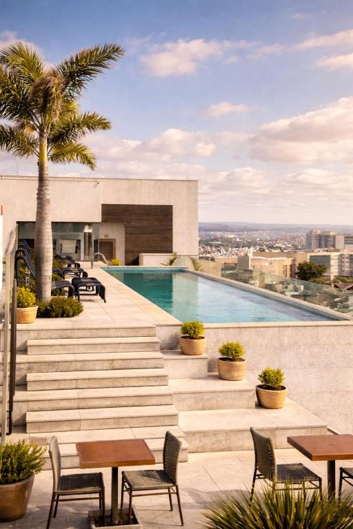 a pool on the roof of a building with tables and chairs at Palazzo Torquetti in Belo Horizonte