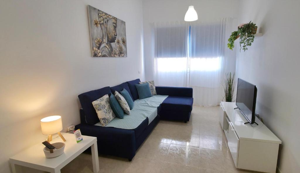 a living room with a blue couch and a tv at La Abundancia in La Restinga