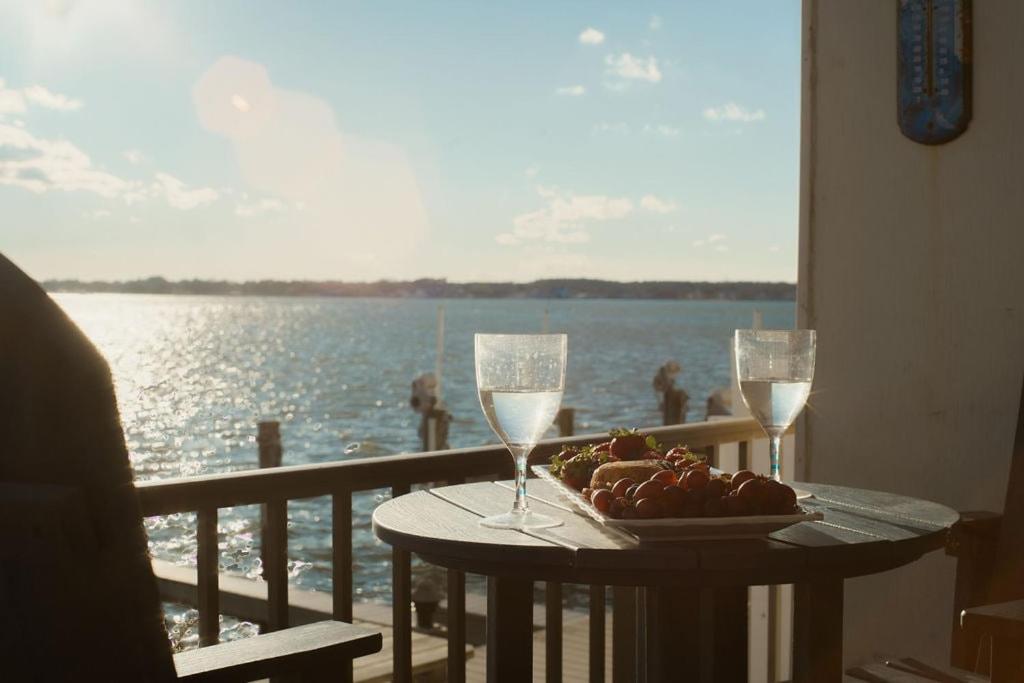 a table with a plate of food and two glasses of wine at Bayfront Bliss Your Waterfront Getaway in Ocean City