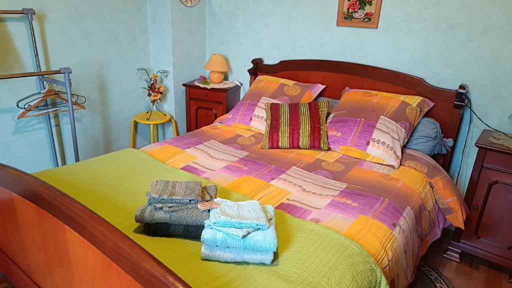 a bedroom with a bed with colorful sheets and towels at Chambres d'hôtes Chez nous in Nantheuil
