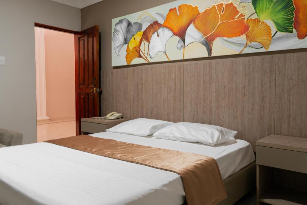 a bedroom with a bed with a painting on the wall at Hotel Paseo Colon in Barranquilla