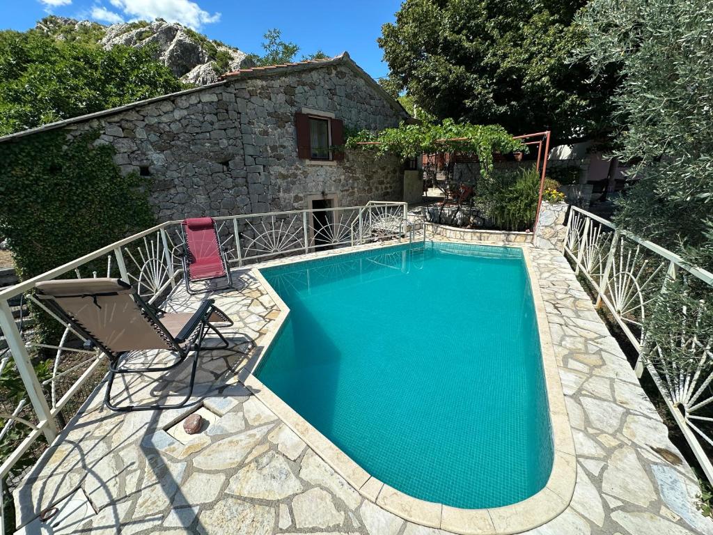 a swimming pool with a chair and a house at Ethno House Ivanovic in Virpazar