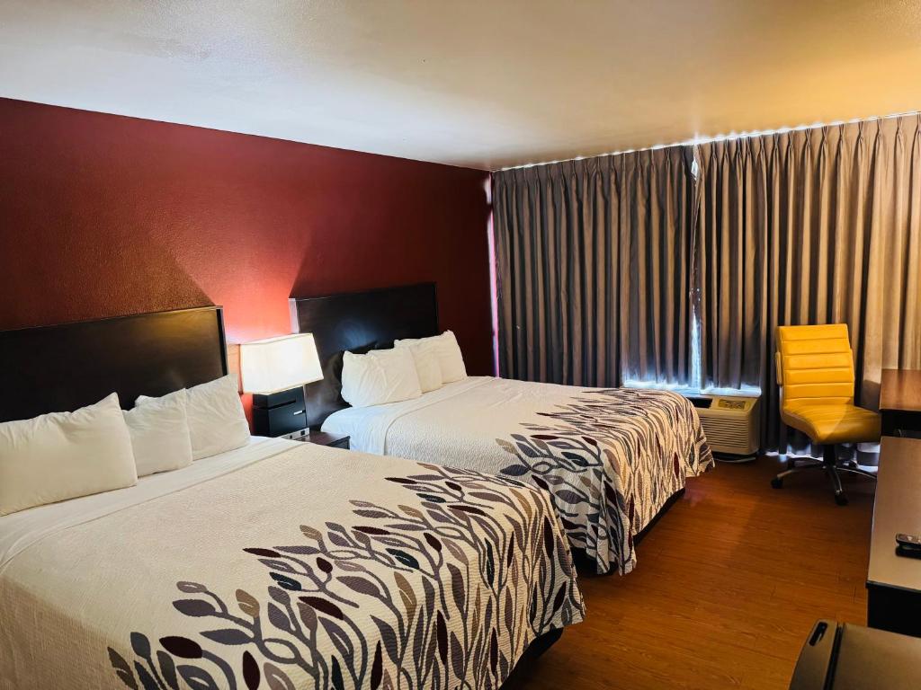 a hotel room with two beds and a chair at Lubbock Regency Inn in Lubbock