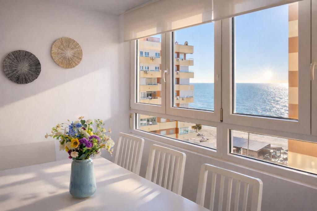 a vase of flowers on a table with a view of the ocean at Casa Ros-PLAYA free parking by Cadiz4Rentals in Cádiz