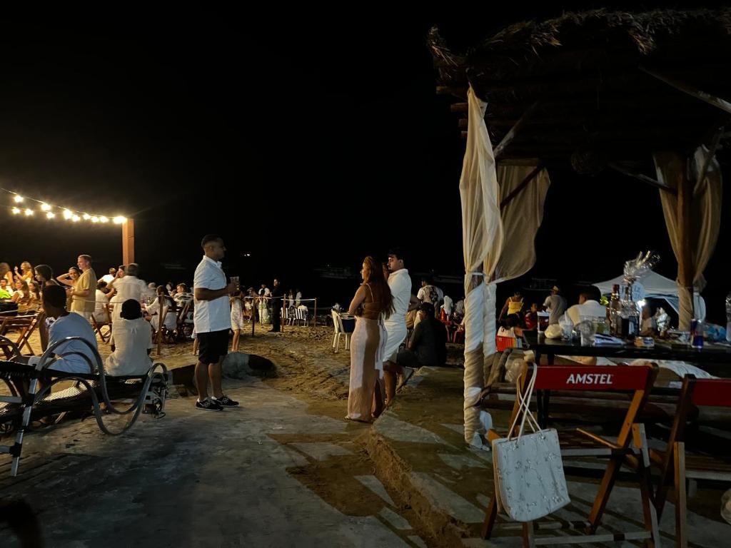 a group of people standing on the beach at night at Flats Raízes da Barra - Terceiro in Maragogi
