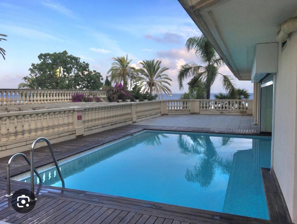 a swimming pool next to a house with a fence at Victoria Palace T2 de 50m2 in Menton
