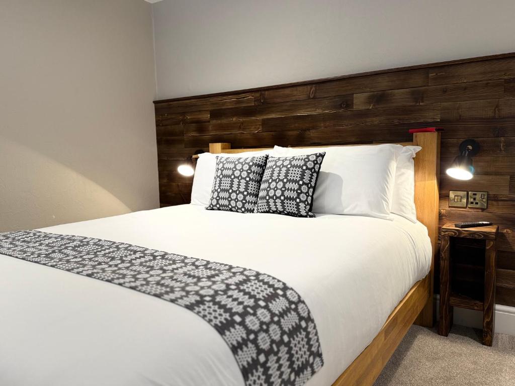 a bedroom with a white bed with a wooden headboard at Tanronnen Inn in Beddgelert