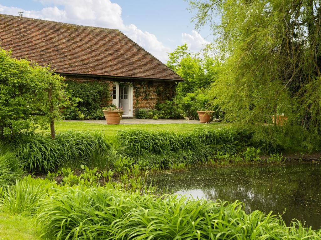 a house with a pond in front of a yard at Leacon Hall Lodge in Orlestone