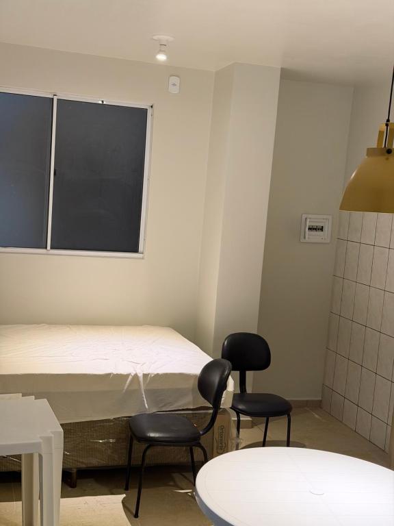 a room with a bed and two chairs and a table at Apartamento Estúdio in Macapá