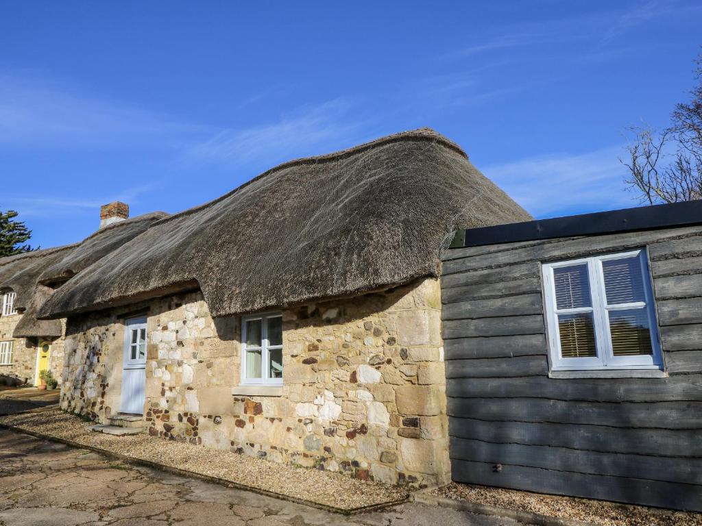 an old stone cottage with a thatched roof at Sheepwash Barn in Freshwater