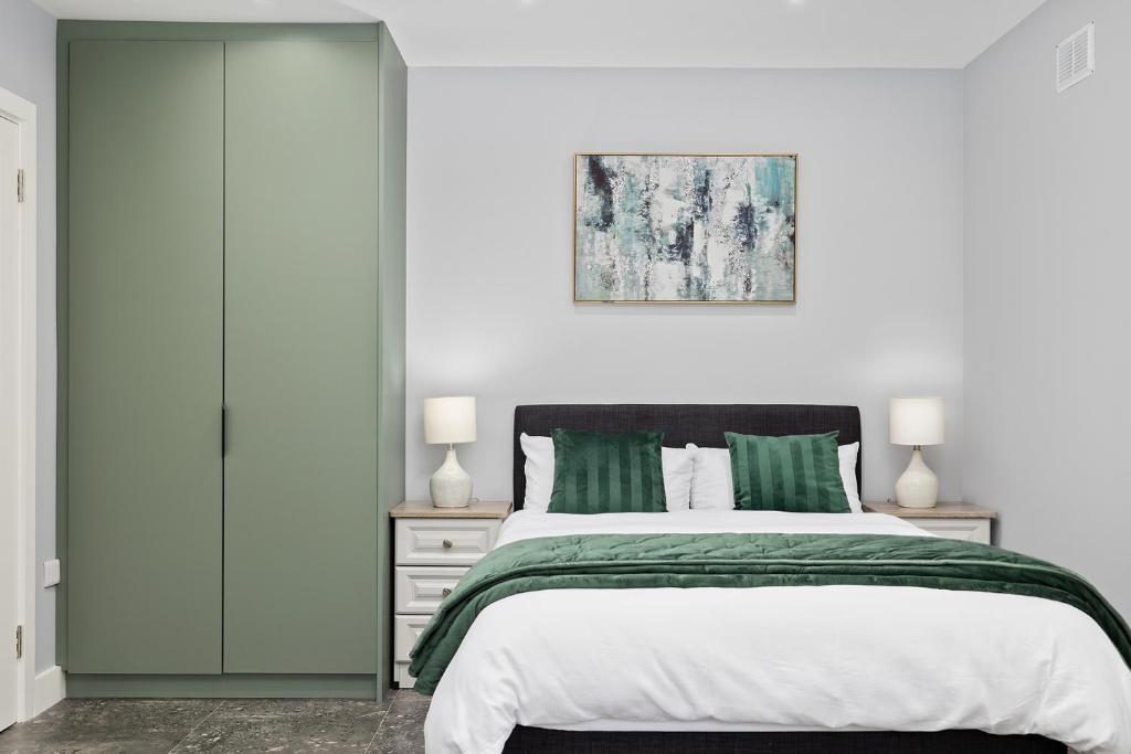 a bedroom with a bed with green sheets and a painting at South Dublin Studio Apartment in Dublin