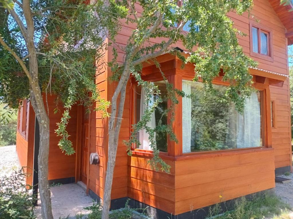 an orange house with a tree in front of it at Cabañas del Oeste in San Carlos de Bariloche