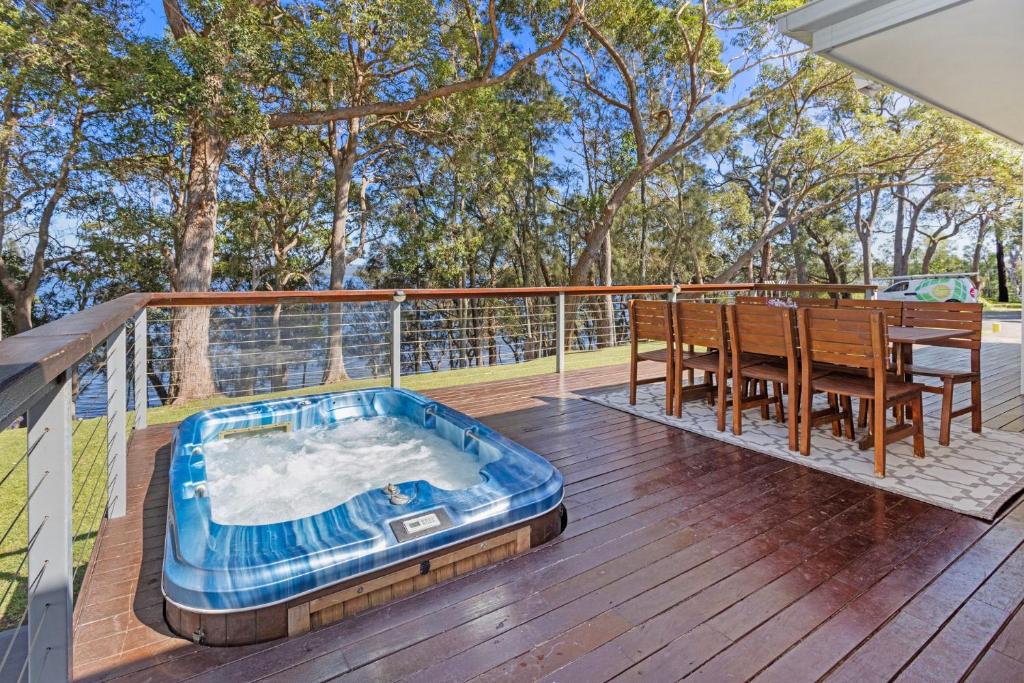 a hot tub on a deck with a table and chairs at Serenity - Pet Friendly with Spa & Waterfront in Sanctuary Point