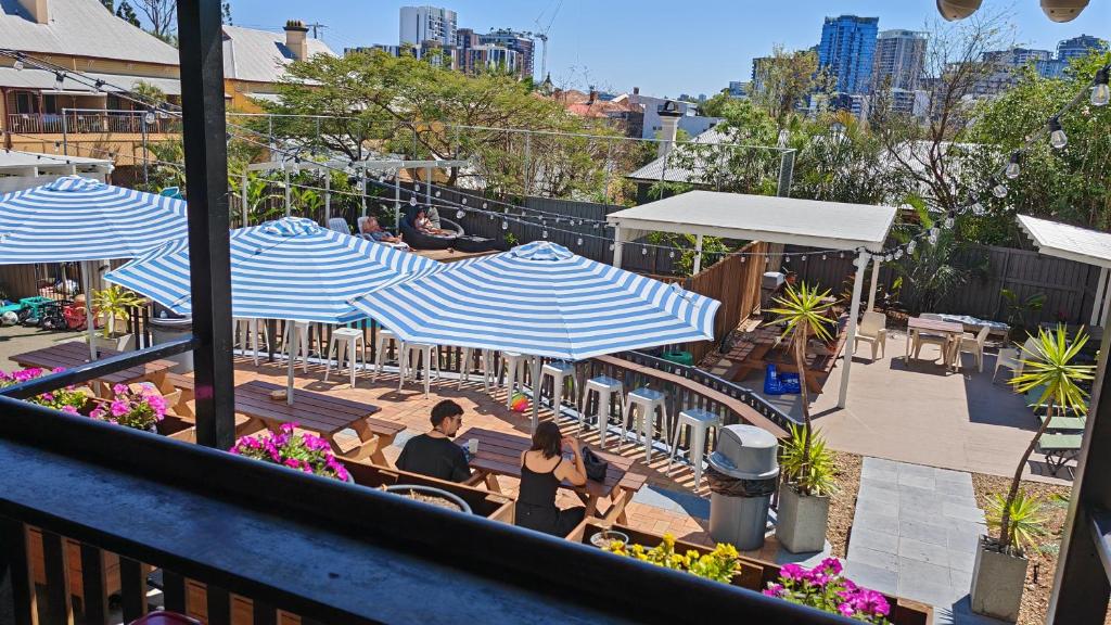 a group of people sitting at tables under umbrellas at Somewhere To Stay Backpackers in Brisbane