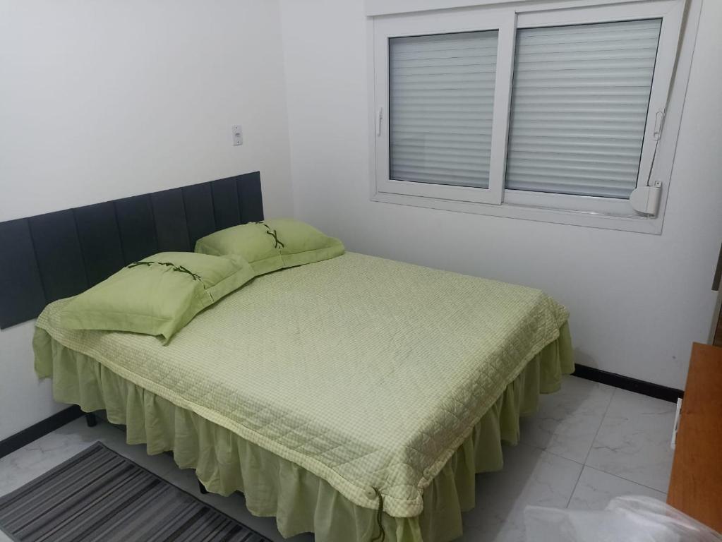 a bedroom with a bed with green sheets and a window at Studio Campeche in Florianópolis