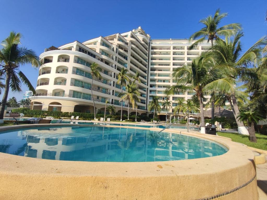 a hotel with a swimming pool in front of a building at BVG Villa 1 Norte in Ixtapa