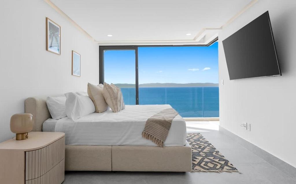 a white bedroom with a bed and a large window at PANAREA - Luxury Beachfront Condos in Bucerias in Bucerías