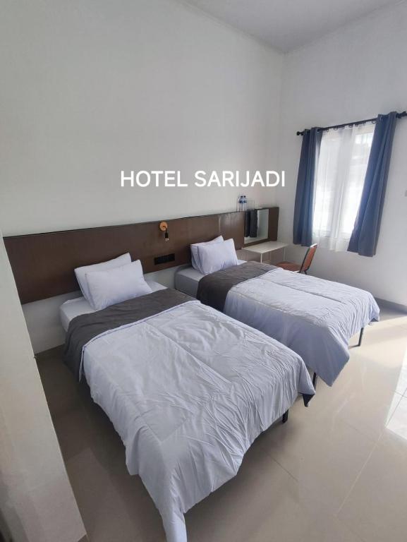 two beds sitting next to each other in a room at Hotel Sarijadi Pangururan in Pangururan