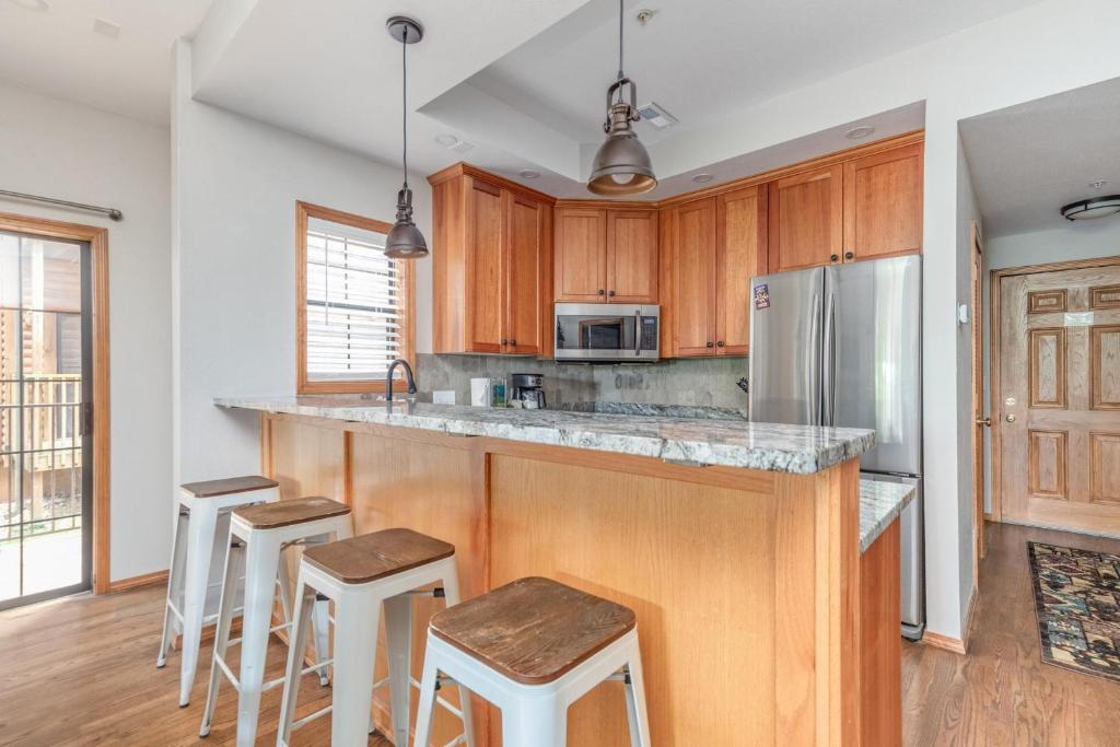 a kitchen with wooden cabinets and a counter with stools at 1BR Village At Indian Point 1104 near SDC-Free Tickets Daily up to $500 in Branson
