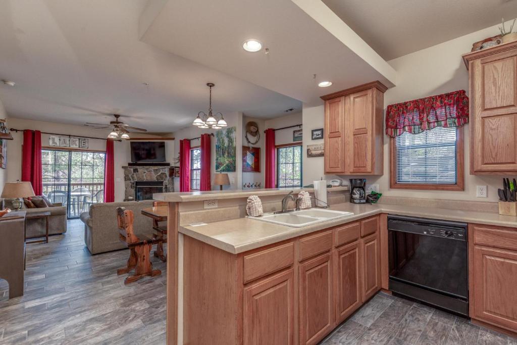 a kitchen with wooden cabinets and a sink and a living room at 1BR Village At Indian Point 2004 near SDC-Free Tickets Daily up to $500 in Branson