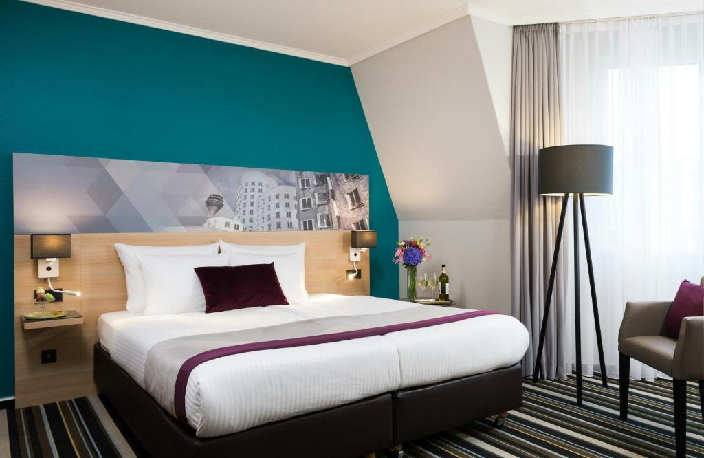 a bedroom with a large bed and a blue wall at Leonardo Hotel Düsseldorf City Center in Düsseldorf