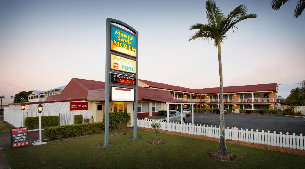 una señal de motel frente a un edificio con una palmera en Mineral Sands Motel en Maryborough