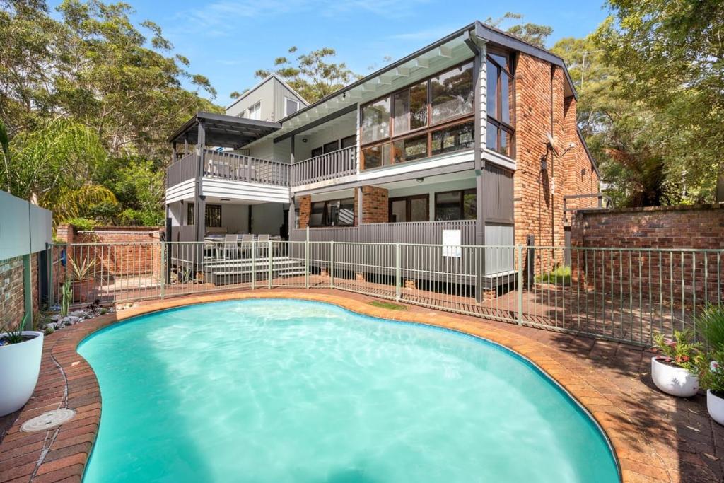 a house with a swimming pool in front of it at Blenheim Beach Retreat in Vincentia
