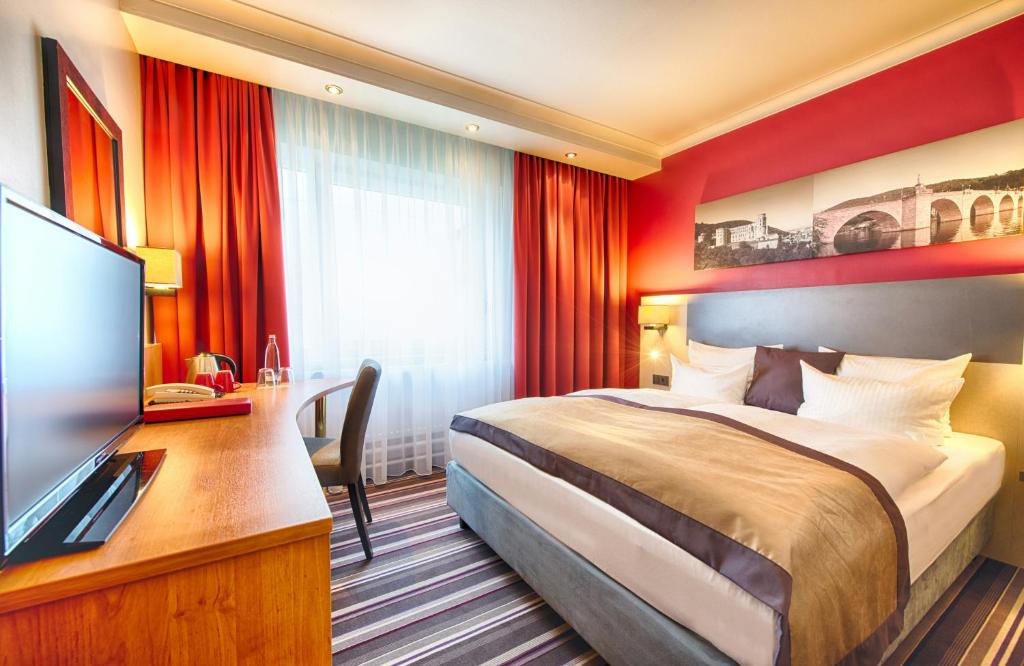 a hotel room with a bed and a flat screen tv at Leonardo Hotel Heidelberg in Heidelberg