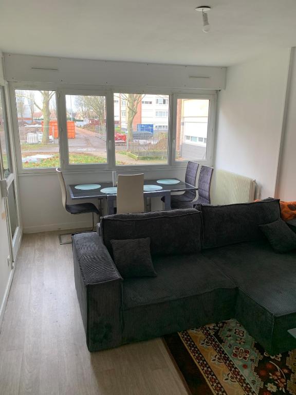 a living room with a couch and tables and windows at Charming, comfortable 3-room apartment in Ronchin