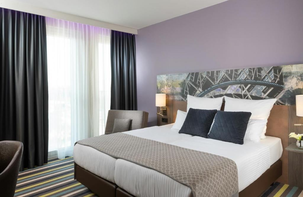 a hotel room with a bed and a chair at Leonardo Hotel Munich City East in Munich