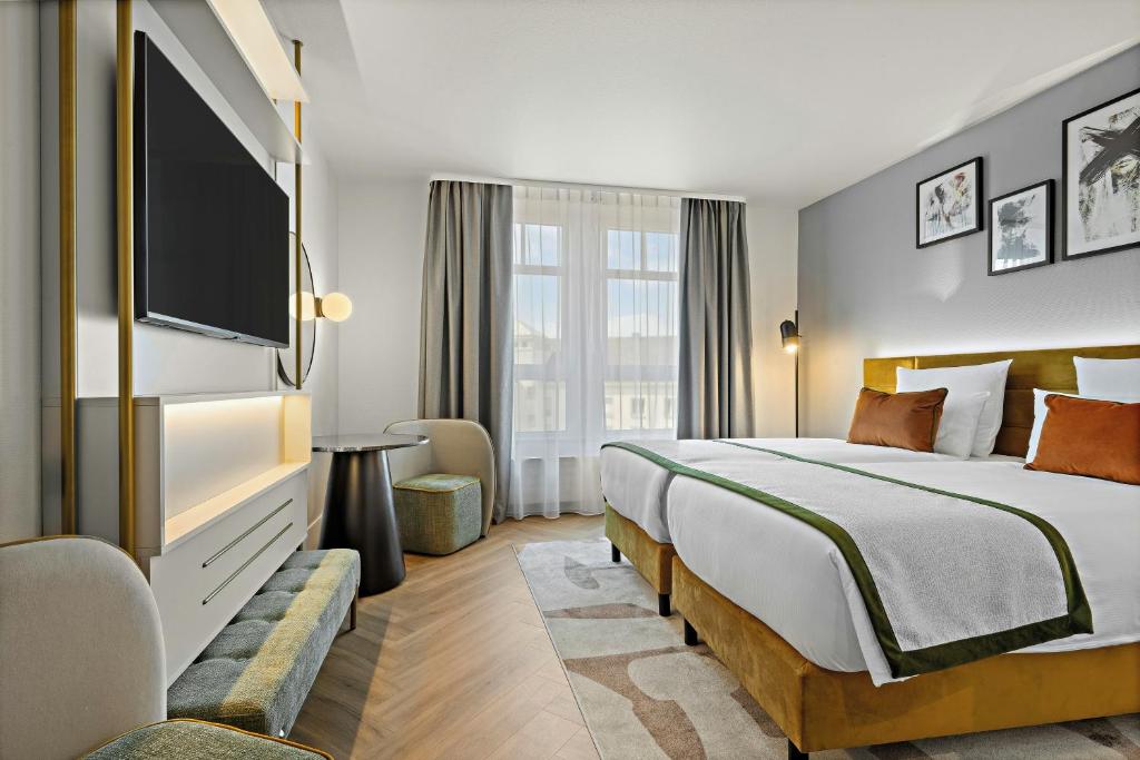 a hotel room with a bed and a flat screen tv at Leonardo Hotel Mainz in Mainz