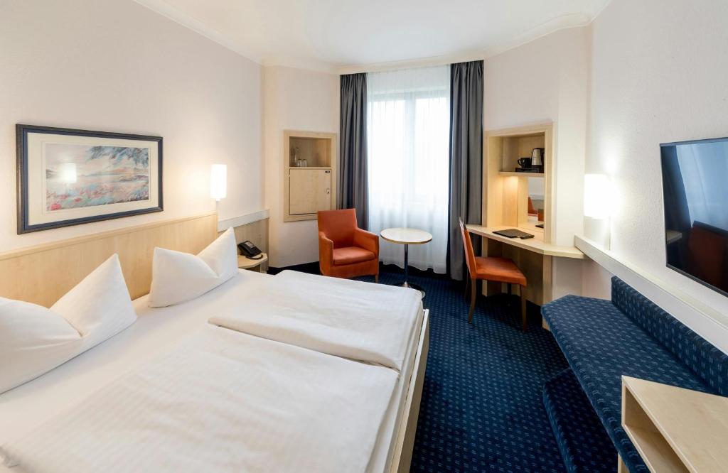a hotel room with a bed and a desk and a television at Hotel Magdeburg City Center by Leonardo Hotels in Magdeburg
