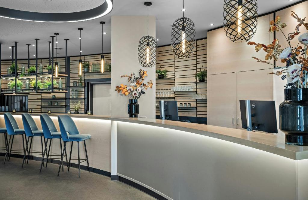 a lobby with a bar with blue stools at Leonardo Hotel Vienna City West in Vienna