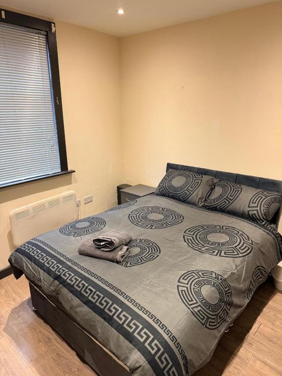 a bedroom with a bed with a blanket and a window at Modern Studios Epsom Station in Epsom