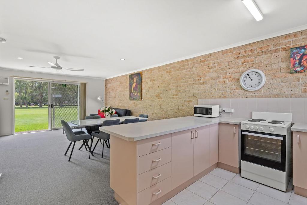 a kitchen and dining room with a brick wall at Ballina Golf Unit in East Ballina
