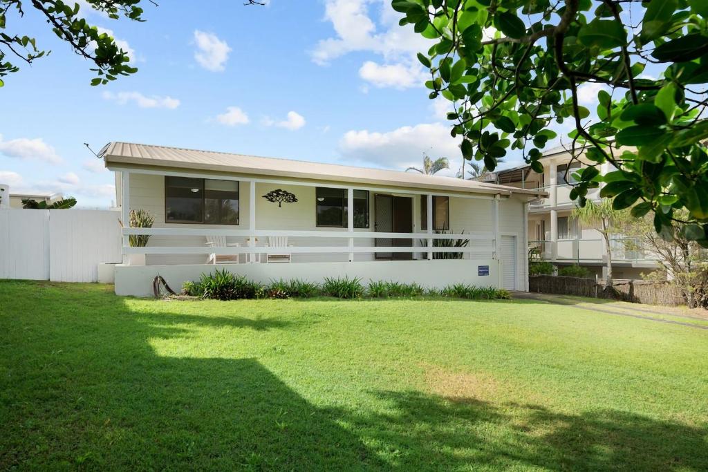 a white house with a lawn in front of it at Baileys Beach House in East Ballina