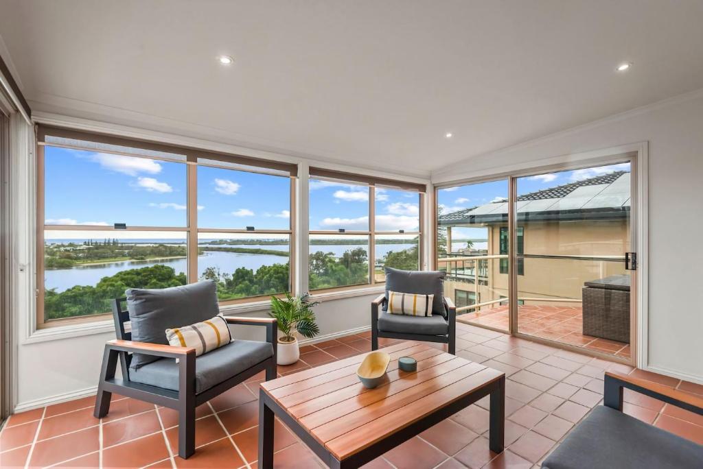 a living room with a table and chairs and windows at Shaws View in East Ballina