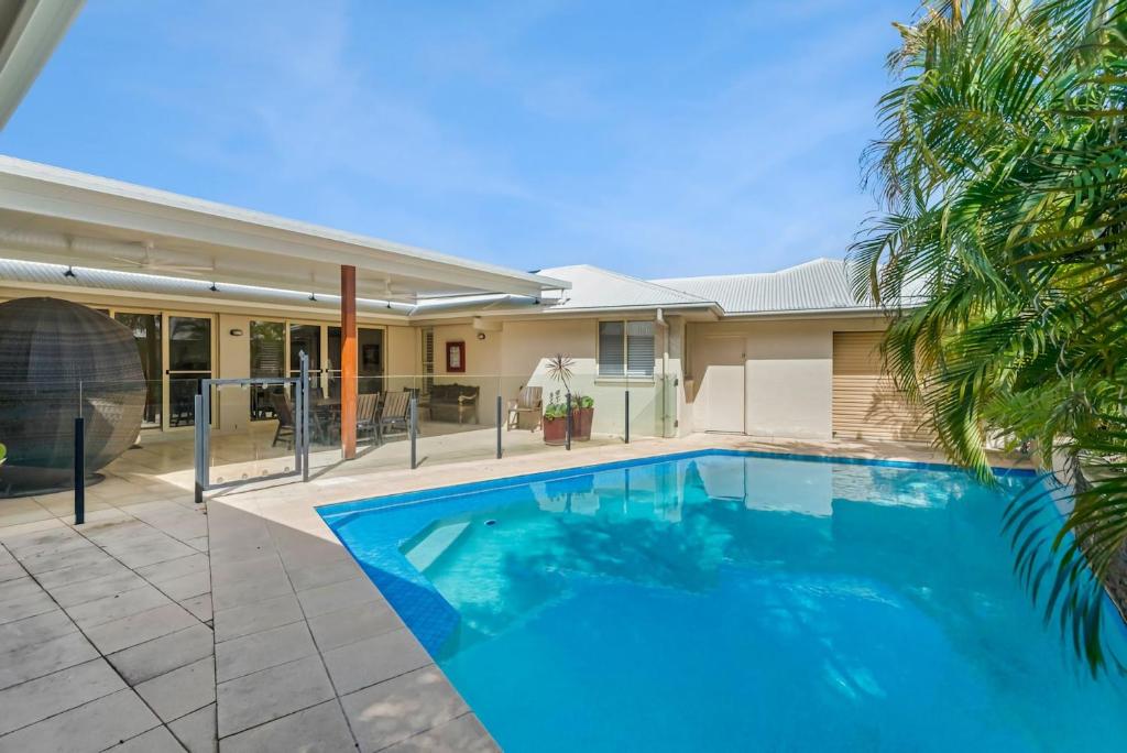 a swimming pool in front of a house at Frangipani Hideaway in Lennox Head