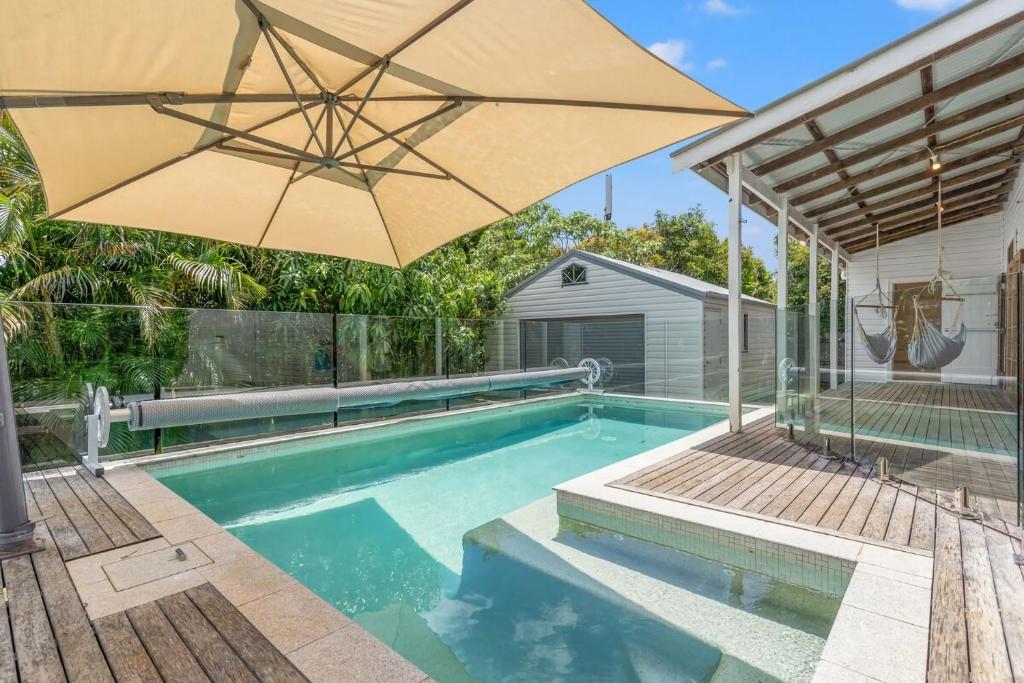 a swimming pool with an umbrella next to a house at Hinterland Views in Lennox Head
