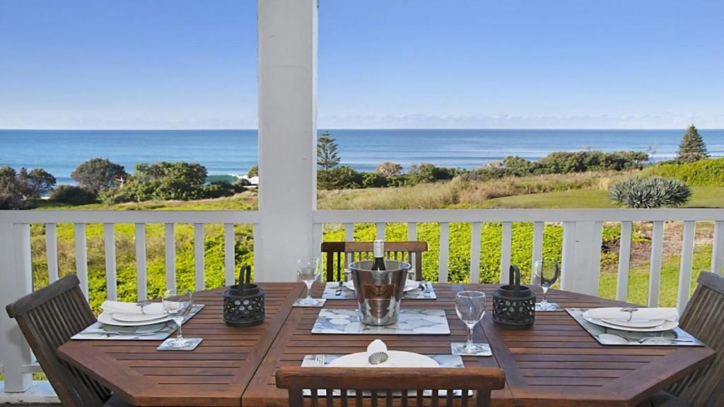 a wooden table on a porch with a view of the ocean at Quarterdeck 23 in Lennox Head