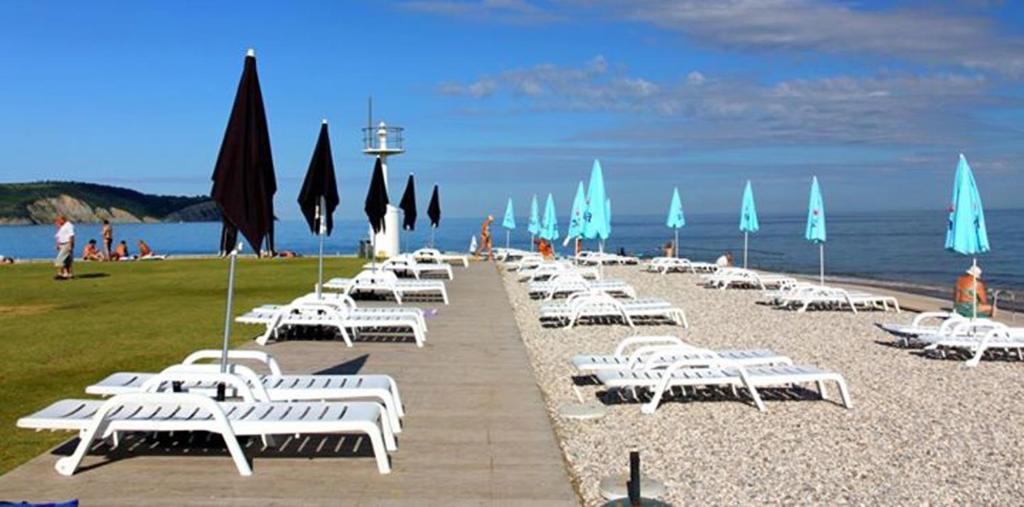 a row of white lounge chairs and umbrellas on a beach at Apartments Kolorček in Izola