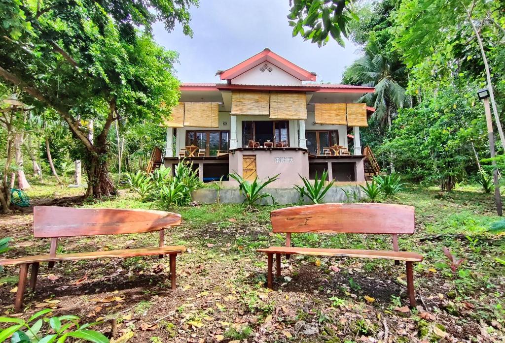 two benches sitting in front of a house at VidFauw Oasis Villa in Naamlong