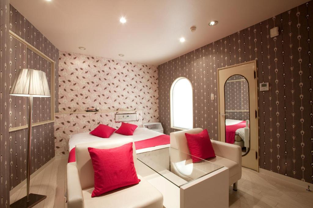 a bedroom with a bed and a couch and a mirror at ホテルラフィネ in Toyonaka