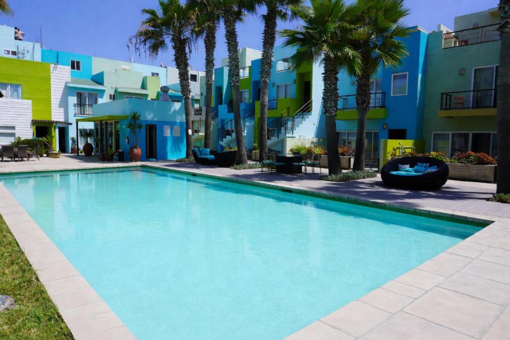 a swimming pool in front of a building with palm trees at Ocean View, Amazing Sunsets, AC, Pool in Tijuana