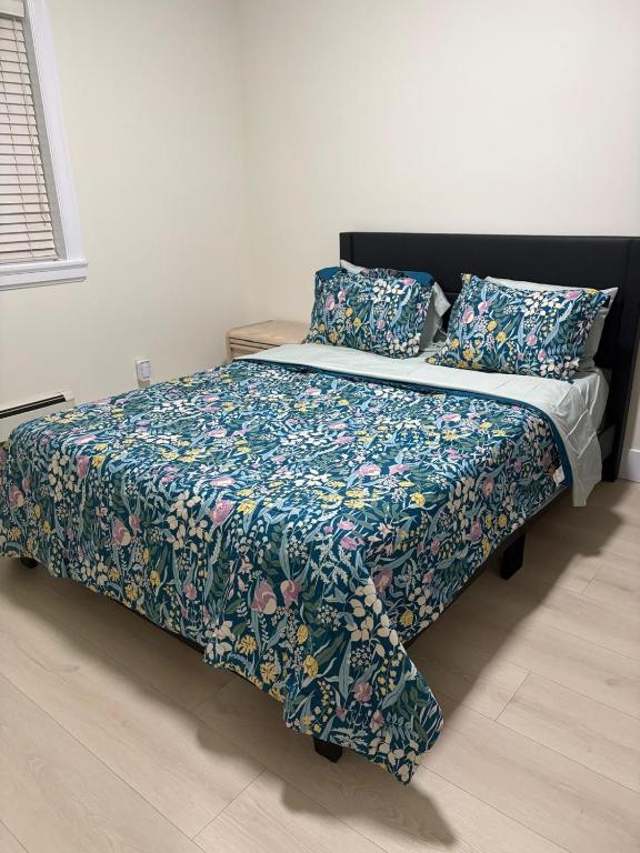 a bedroom with a bed with a floral comforter and pillows at Cozy Home in Surrey