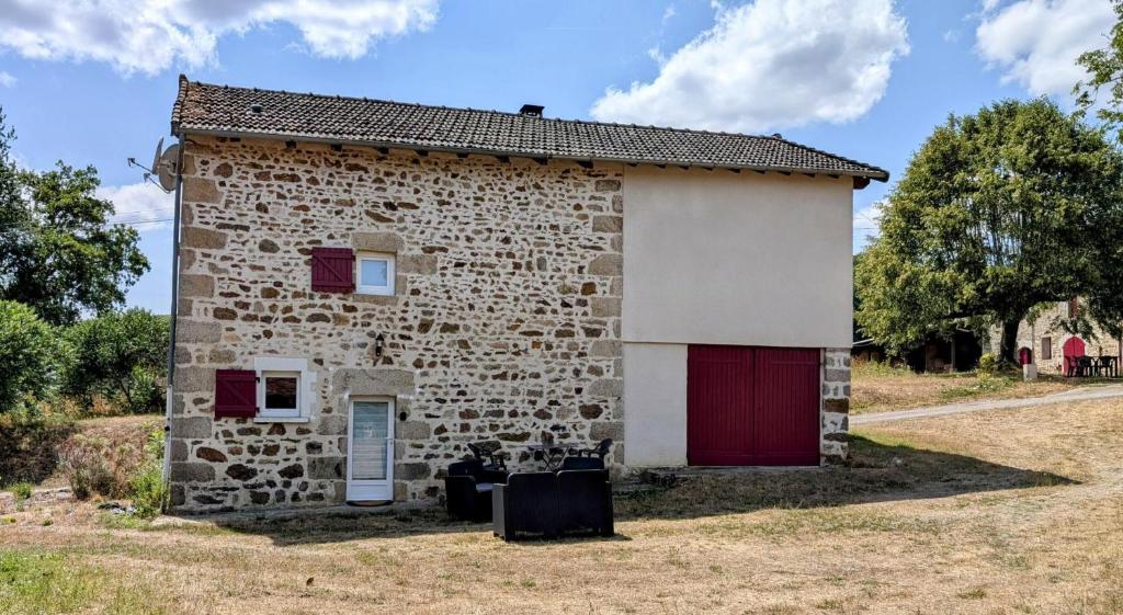 a small stone building with a red door at Petit villetelle in Cheissoux
