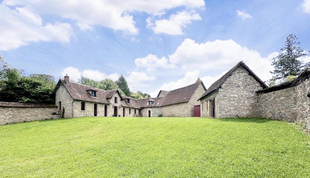 an old stone building with a grass field in front at La pommeraie in Château-Chervix