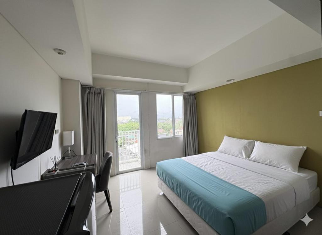a bedroom with a bed and a tv and a window at Studio Bogor Icon Apt wifi&pool in Kedunghalang